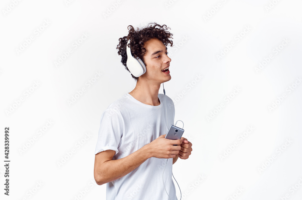 funny guy with curly hair in a white t-shirt listens to music technology entertainment funny guy with curly hair in a white t-shirt listens to music technology entertainment