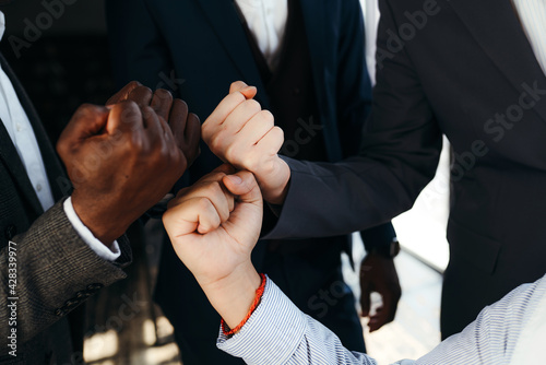 Close-up photo. Male hands of black and European businessmen clenched into fists touching each other