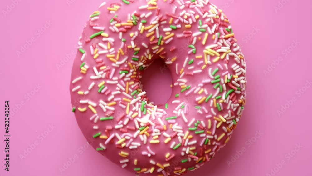 Extreme close up bright circle donut covering by icing glaze isolated on pink. 4k Dragon RED camera Extreme close up bright circle donut covering by icing glaze isolated on pink. 4k Dragon RED camera