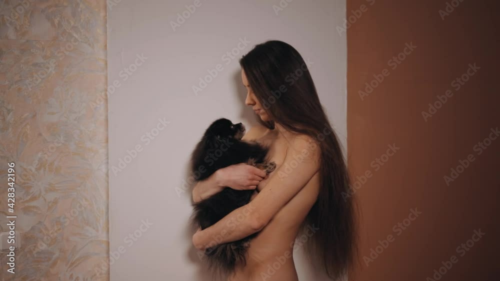 Vidéo Stock Young nudist woman holding her funny licking little spitz dog | Adobe Stock