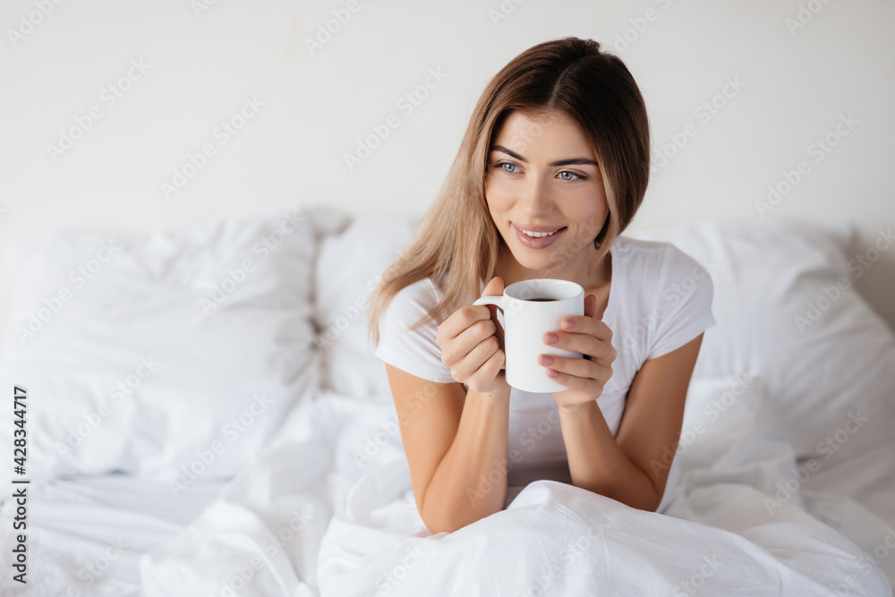 Joyous young lady starting new day in bed with coffee Joyous young lady starting new day in bed with coffee