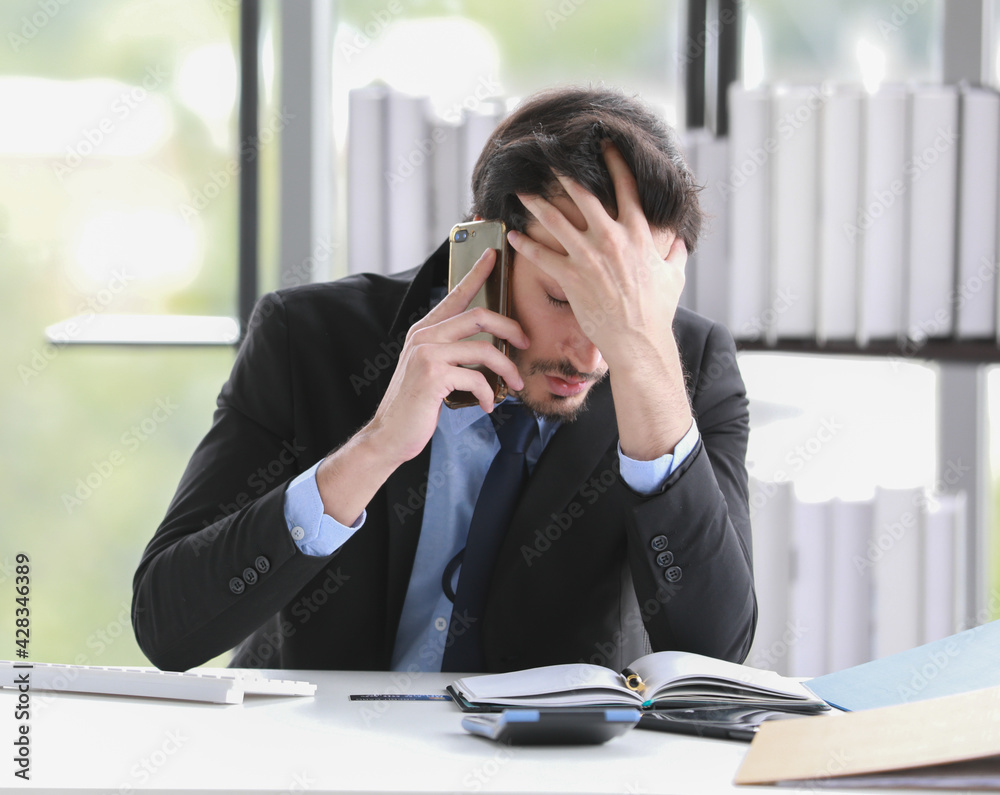 Stressed businessman answering phone call in office Stressed businessman answering phone call in office