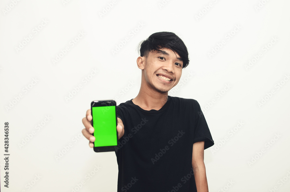 Asian man wearing casual black t-shirt pointing at green screen cellphone Asian man wearing casual black t-shirt pointing at green screen cellphone