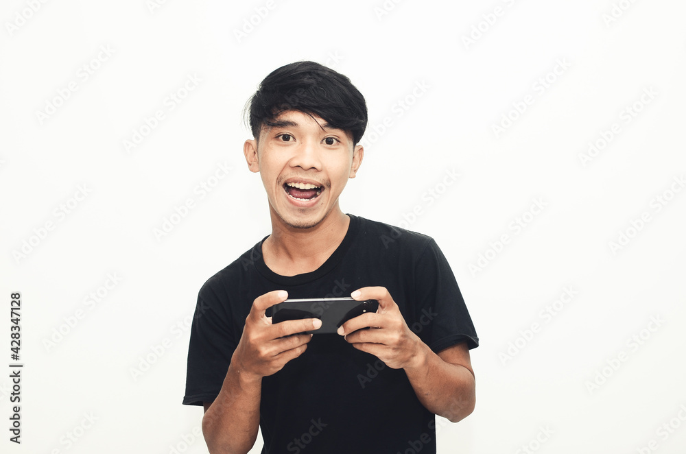 An Asian man wearing a casual black shirt plays games on his phone An Asian man wearing a casual black shirt plays games on his phone