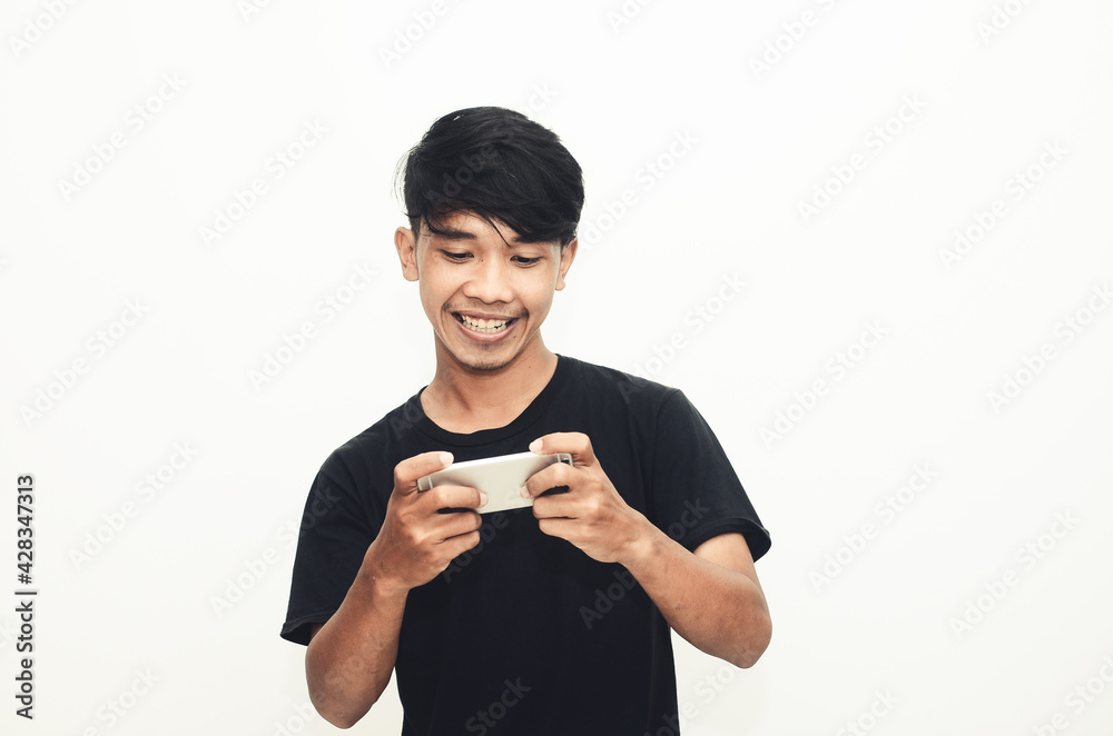 An Asian man wearing a casual black shirt plays games on his phone An Asian man wearing a casual black shirt plays games on his phone