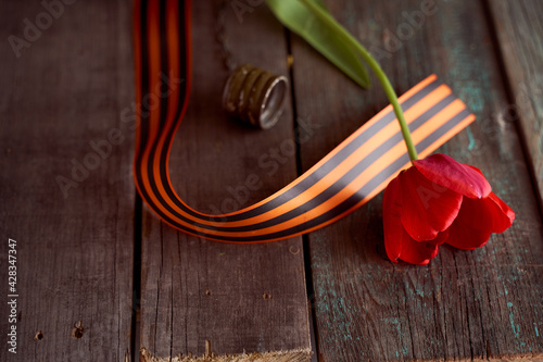 Red tulip in a soldier's military flask with St. George ribbons
