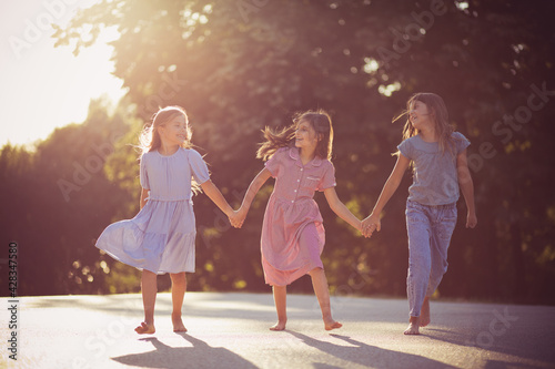 Three little girls spending time in nature. Running and holding hands.