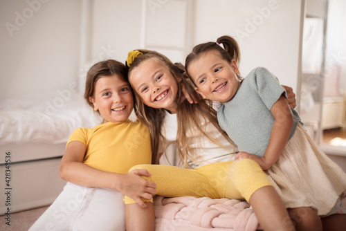 Portrait of three little girls in room.