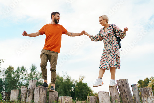 Cheerful active coupe walking on stumps on blue sky background