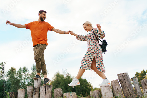 Cheerful active coupe walking on stumps on blue sky background