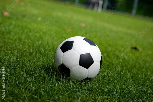 Football placed on a grass pitch in the afternoon awaiting for teams practicing or matches in a tournament.
