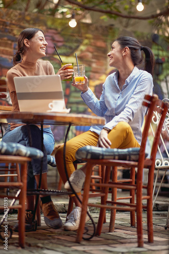 Two female friends toasting while having a drink at the bar. Leisure, bar, friendship, outdoor