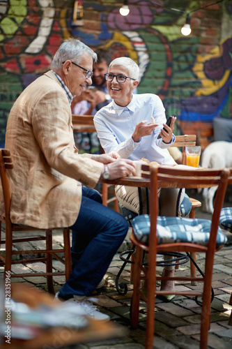 An older couple watching a smartphone content while having a drink in the bar. Leisure  bar  friendship  outdoor