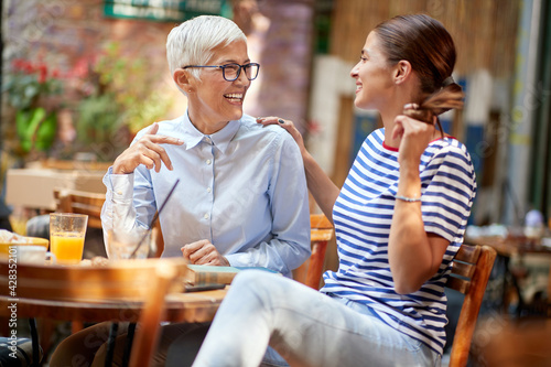 Two female friends of different generations have a friendly talk while they have a drink in the bar. Leisure  bar  friendship  outdoor