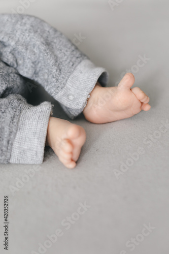 Little feet of newborn baby with copy space on gray background, happy parents concept