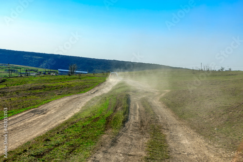 Car on country road raises dust . Rural journey 