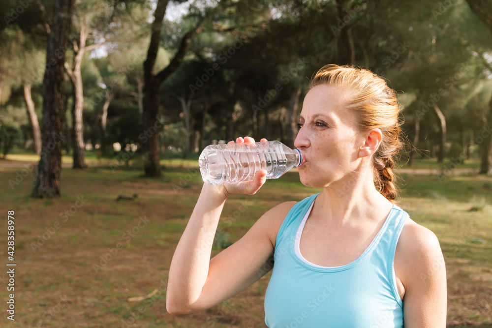 Fitness woman drinking a bottle of water while doing sports outdoors Fitness woman drinking a bottle of water while doing sports outdoors