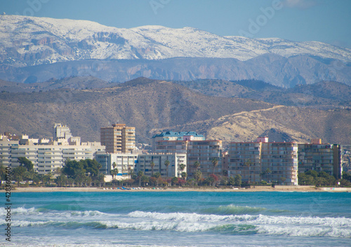 Snow at the mountains and sea at the beach of Campello, Alicante Province, Costa Blanca, Spain photo