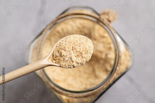 nutritional yeast in flakes, deactivated, not live, B vitamins, in a jar, focus on a spoon, close-up, top view photo