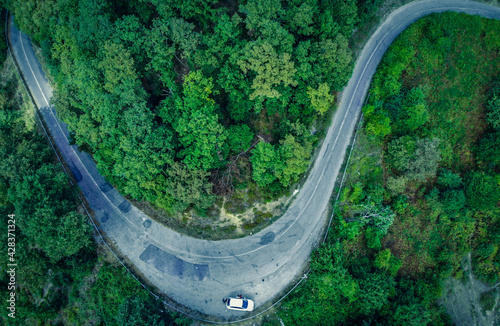A curled road in the greens. Drone view of the forest. It's a curvy road. A road through the forest. © osmanozeroz