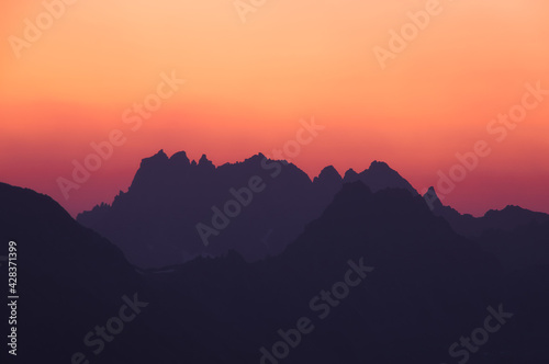 orange colours sunset at the black silhouette mountains