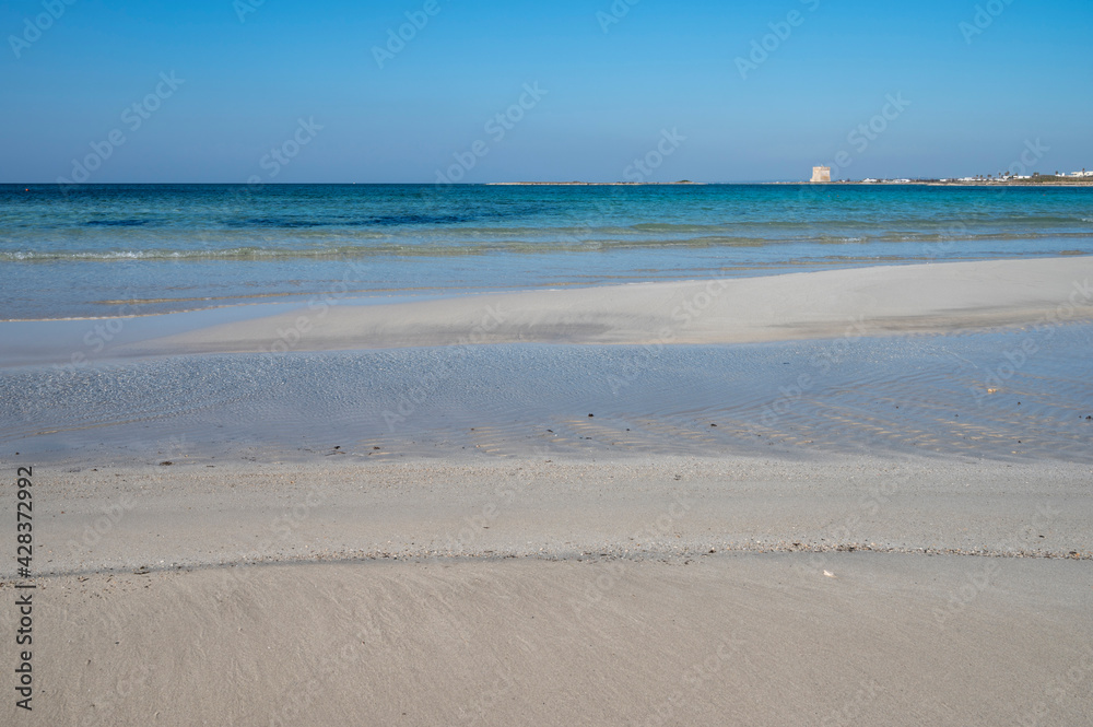 Sabbia bianca con mare trasparente e cielo azzurro.