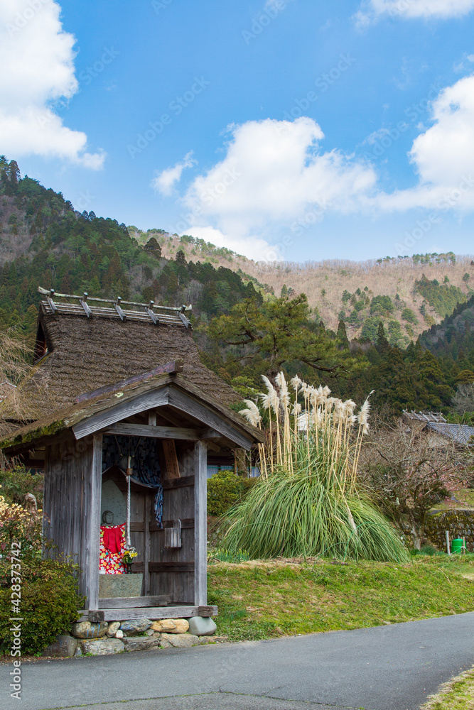 Jizo and an old house with a thatched roof in Kitamura, Miyama Kayabuki no Sato, Nantan City, Kyoto Prefecture, Japan