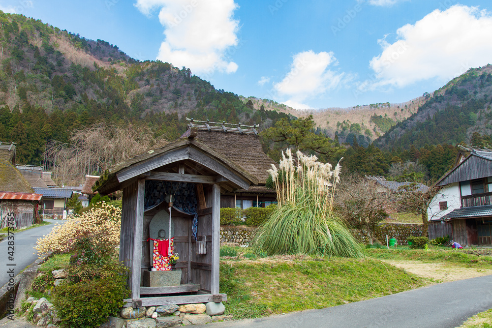 Φωτογραφία Jizo and an old house with a thatched roof in Kitamura, Miyama Kayabuki no Sato,