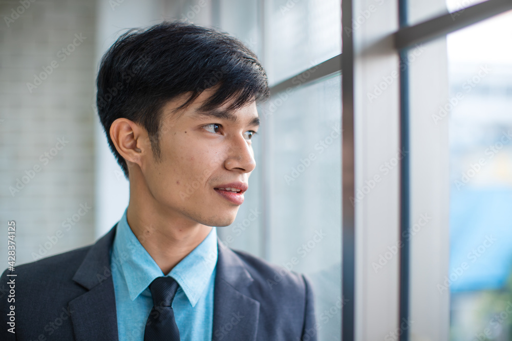 Positive Asian businessman leaning on brick wall