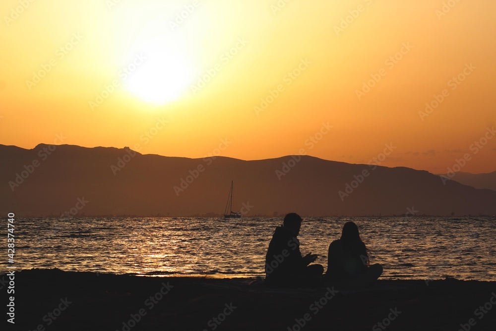 Young couple of lovers looking at the sea on sunset