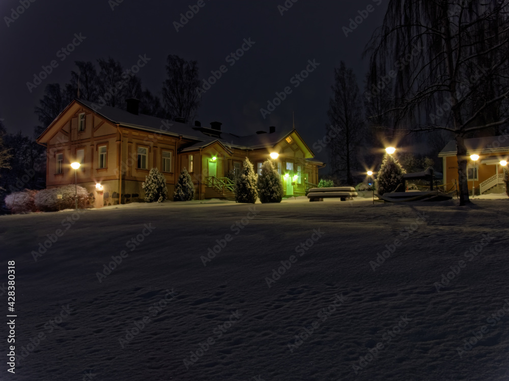 Beautiful wooden house in the winter evening in the snow with illumination.