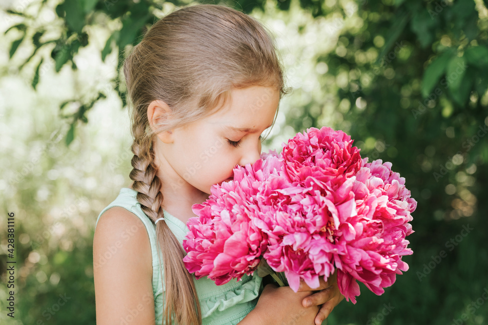 portrait of a happy cute little caucasian seven year old kid girl, holds in hands and smell and enjoying a bouquet of pink peony flowers in full bloom on the background of nature portrait of a happy cute little caucasian seven year old kid girl, holds in hands and smell and enjoying a bouquet of pink peony flowers in full bloom on the background of nature