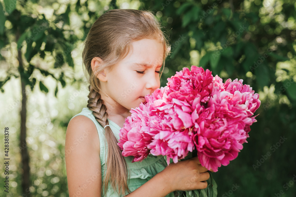 portrait of a happy cute little caucasian seven year old kid girl, holds in hands and smell and enjoying a bouquet of pink peony flowers in full bloom on the background of nature portrait of a happy cute little caucasian seven year old kid girl, holds in hands and smell and enjoying a bouquet of pink peony flowers in full bloom on the background of nature