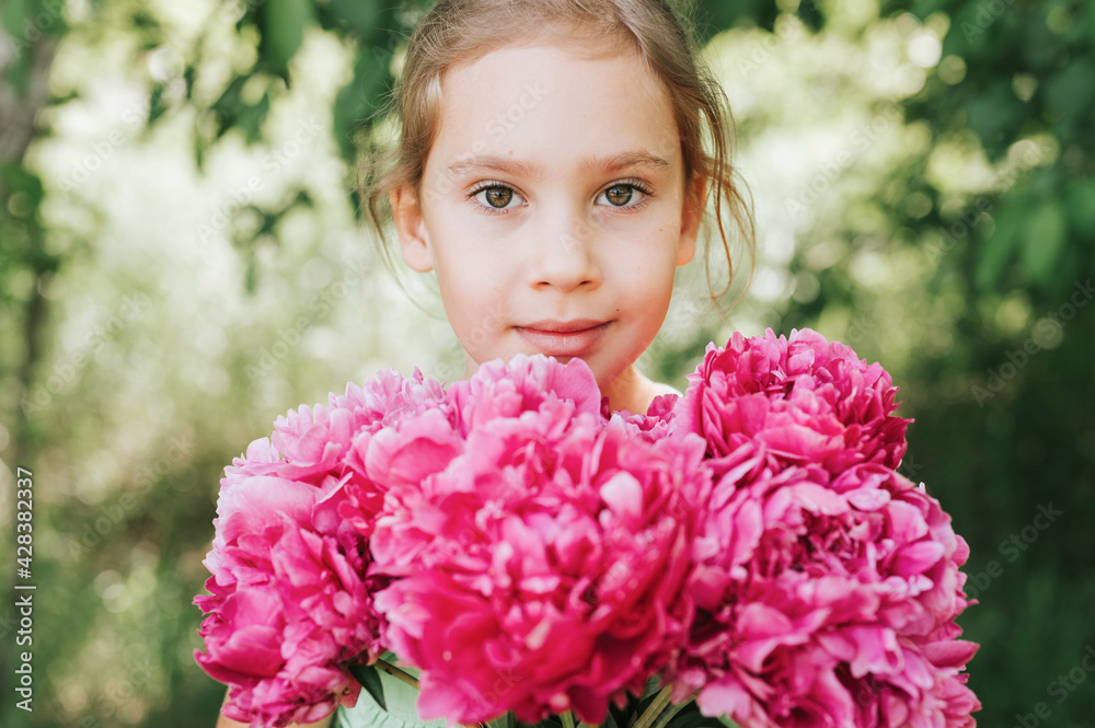 portrait of a happy cute little caucasian seven year old kid girl, holds in hands a bouquet of pink peony flowers in full bloom on the green background of nature portrait of a happy cute little caucasian seven year old kid girl, holds in hands a bouquet of pink peony flowers in full bloom on the green background of nature