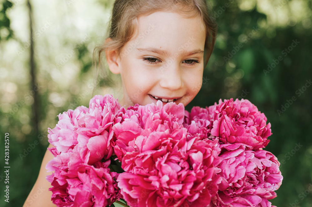 portrait of a happy cute little caucasian seven year old kid girl, holds in hands and smell and enjoying a bouquet of pink peony flowers in full bloom on the background of nature portrait of a happy cute little caucasian seven year old kid girl, holds in hands and smell and enjoying a bouquet of pink peony flowers in full bloom on the background of nature