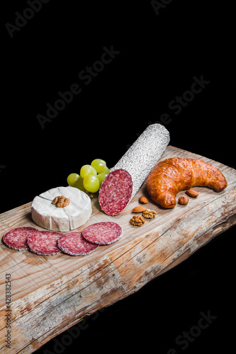 Dry meat sausage on a wooden plate with vegetables