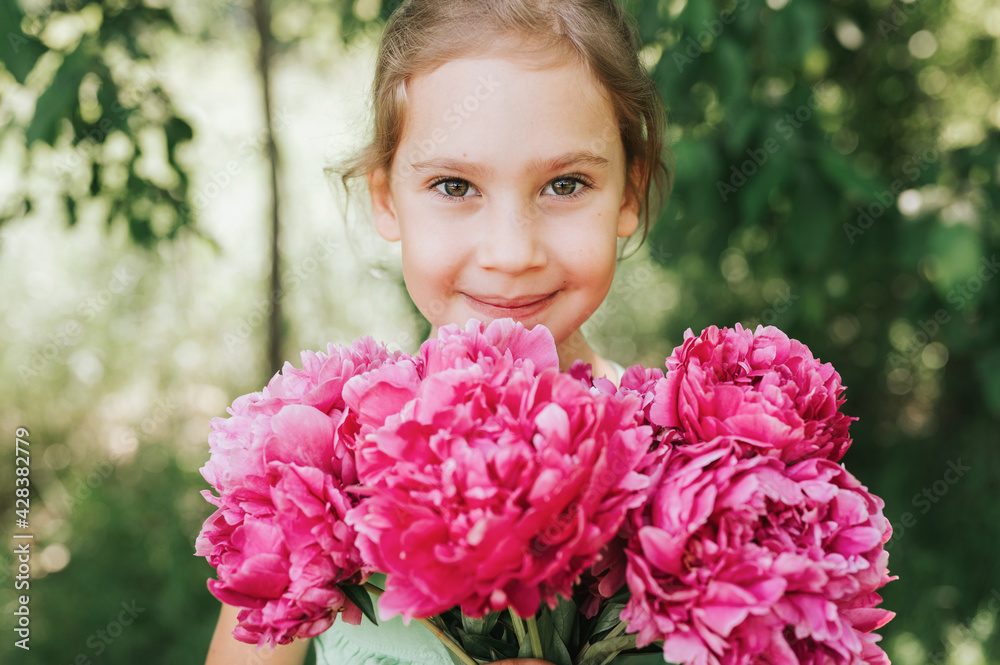 portrait of a happy cute little caucasian seven year old kid girl, holds in hands a bouquet of pink peony flowers in full bloom on the green background of nature portrait of a happy cute little caucasian seven year old kid girl, holds in hands a bouquet of pink peony flowers in full bloom on the green background of nature