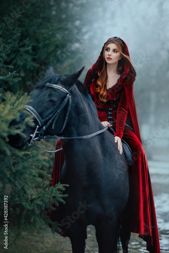 Photography Medieval woman princess in red dress sits astride black steed horse