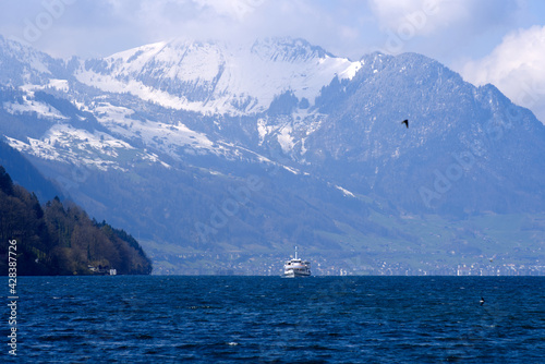 Ship on lake Vierwaldstättersee with snow capped Swiss alps in the background. Photo taken April 14th, 2021, Brunnen, Switzerland.