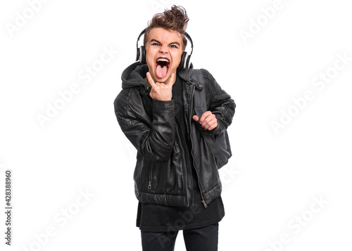 Teen boy in headphones with spooking make-up making Rock Gesture, isolated on white background. Teenager in style of punk goth dressed in black screaming and shouting, doing heavy metal rock sign