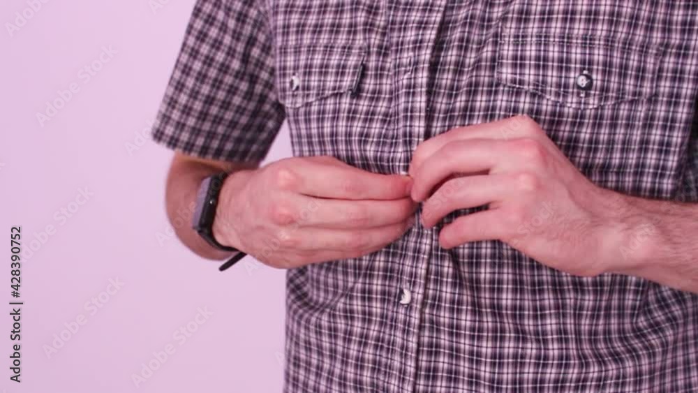 A man in a plaid shirt buttoning the buttons A man in a plaid shirt buttoning the buttons