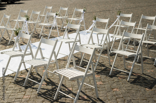 Close up of beautiful wedding ceremony with white wood chairs and carpet