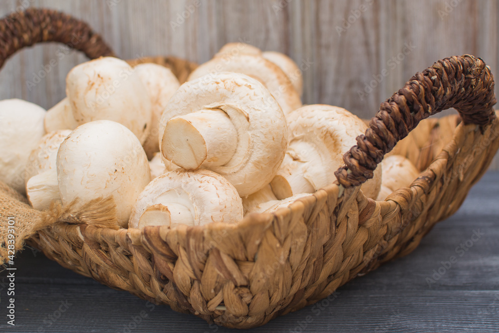 Fresh champignons in a wicker basket on a dark wooden background. Fresh champignons in a wicker basket on a dark wooden background.