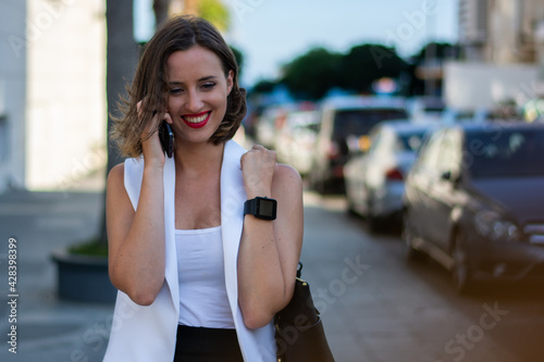 Young woman walking in city and talking on mobile phone