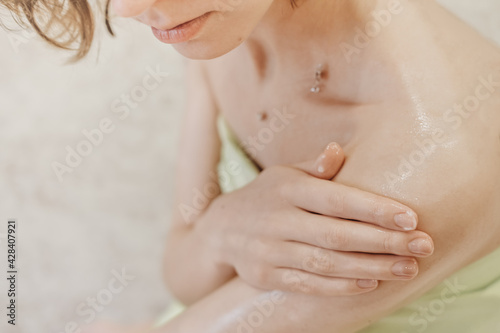 woman applying body butter on her shoulder. crop view. nourishing shea butter for smooth skin after bath. home spa and me time concept