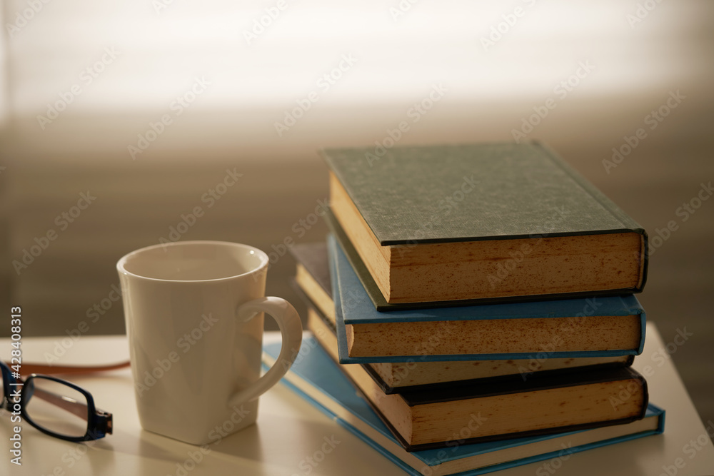 stack of book and cup coffee by window ,evening stack of book and cup coffee by window ,evening