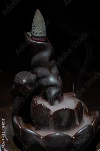 Ceramic backflow incense burner in the form of lotus flower. Incense cones holder. Dark mystic concept.
