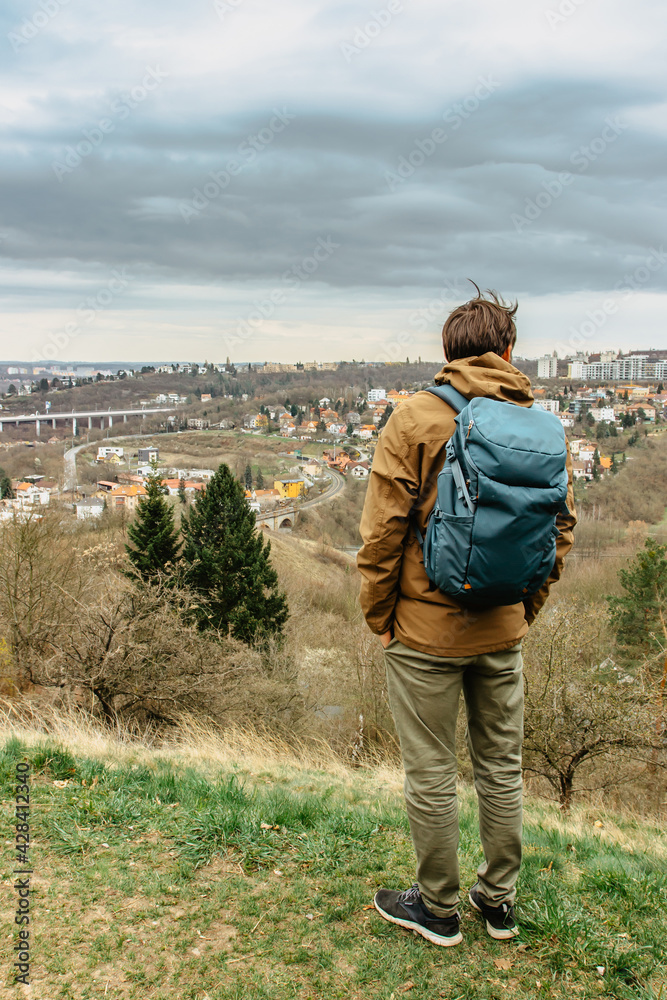 Man with backpack enjoying view of Prokopske valley nature reserve and residential district,Prague,Czech Republic.Attractive landscape with deep valleys,limestone rocks,hiking trails.Active lifestyle