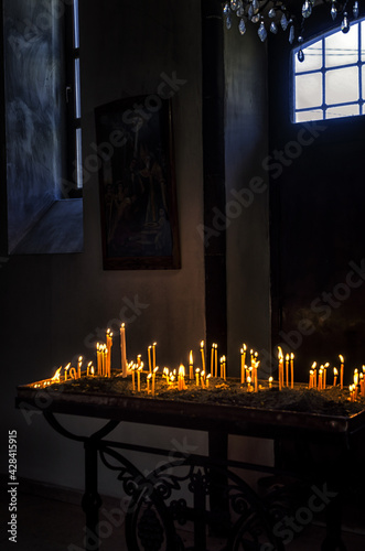 Vertical shot of lit votive candles in a church for dead loved on photo