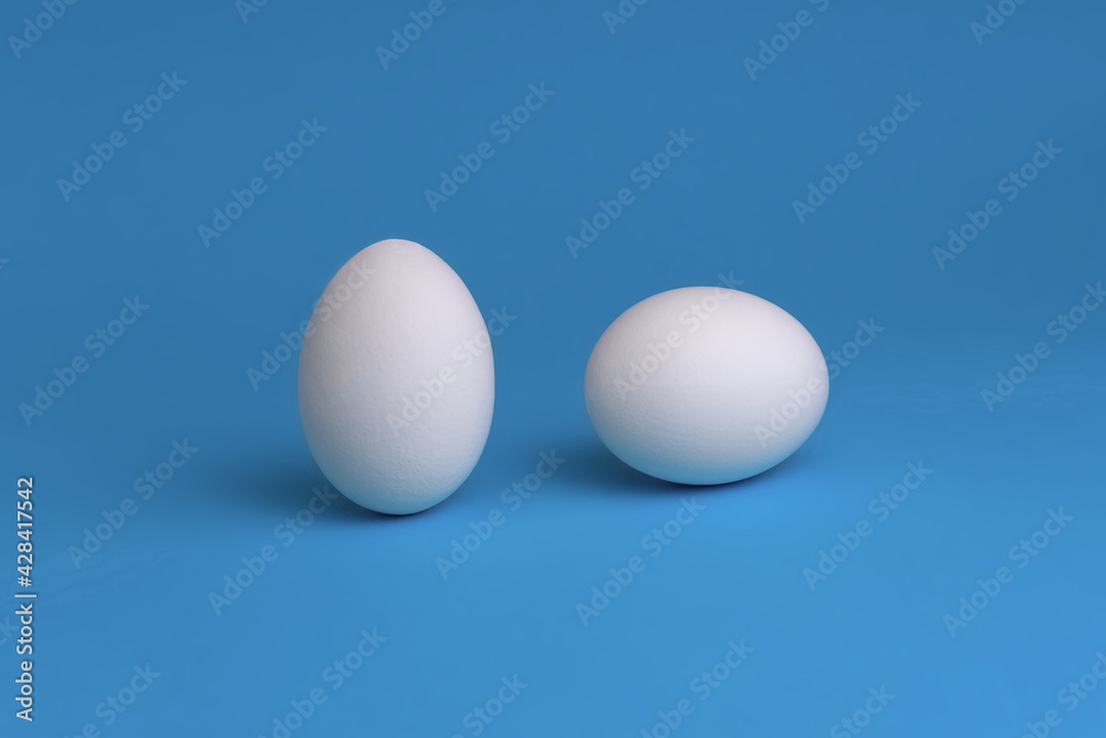 White eggs on a blue background. The concept of minimalism. Side view. A card with a copy of the place for the text. White eggs on a blue background. The concept of minimalism. Side view. A card with a copy of the place for the text.